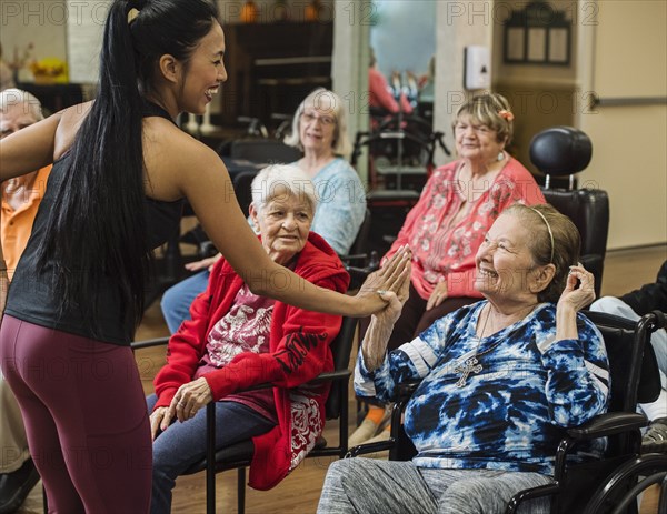 Smiling fitness instructor high-fiving smiling senior woman