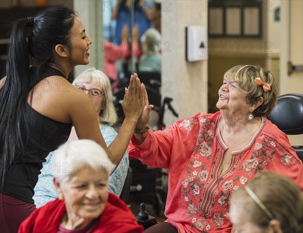 Smiling fitness instructor high-fiving smiling senior woman