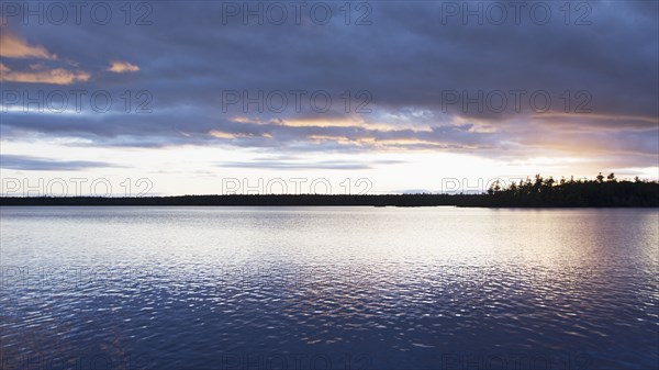 Silhouette of trees and lake at sunset