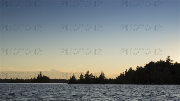 Silhouette of trees and lake at sunset