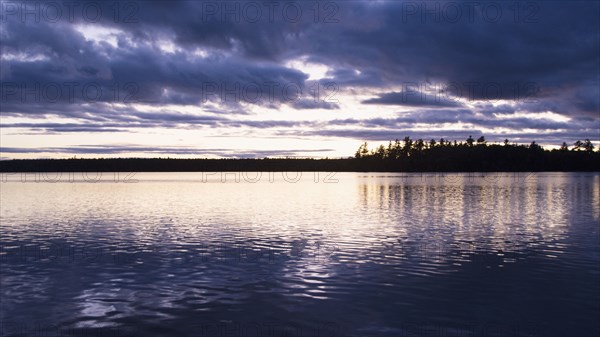 Silhouette of trees and lake at sunset