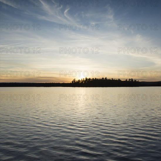 Silhouette of trees and lake at sunset