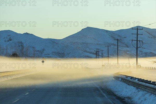 Fog on road by snowy mountains