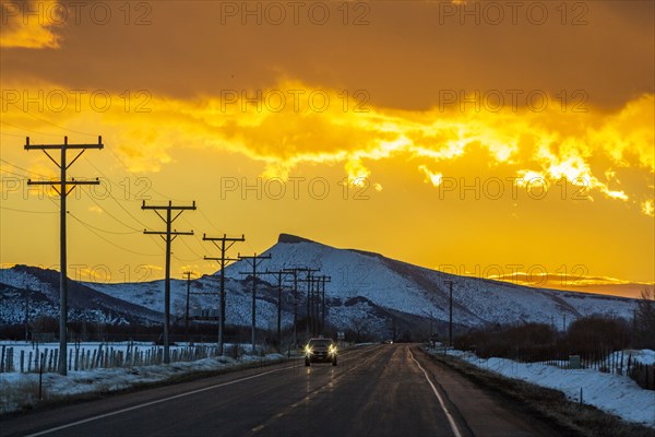 Car on road under dramatic sky at sunrise