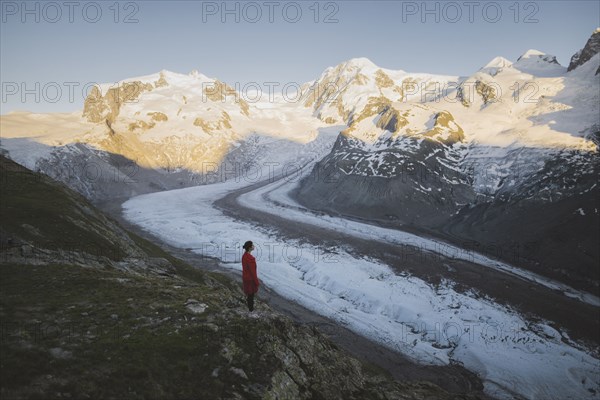 Woman standing on rock by Gorner Glacier in Valais, Switzerland