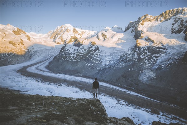 Man standing on rock by Gorner Glacier in Valais, Switzerland