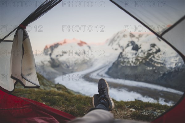 Man lying inside tent with Gorner Glacier in distance in Valais, Switzerland