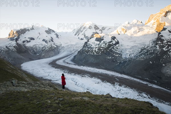 Woman standing on rock by Gorner Glacier in Valais, Switzerland