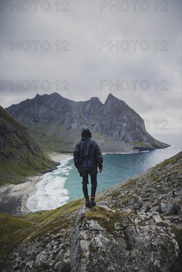 Man standing on rock by Kvalvika Beach in Lofoten Islands, Norway