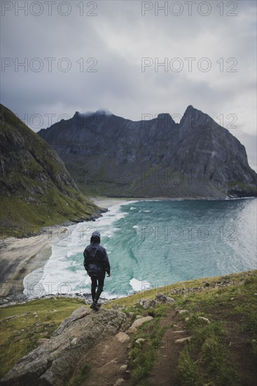 Man standing on rock by Kvalvika Beach in Lofoten Islands, Norway