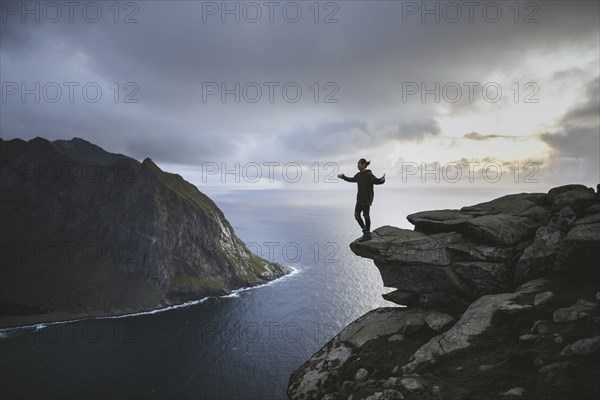 Man standing on cliff at Ryten mountain in Lofoten Islands, Norway