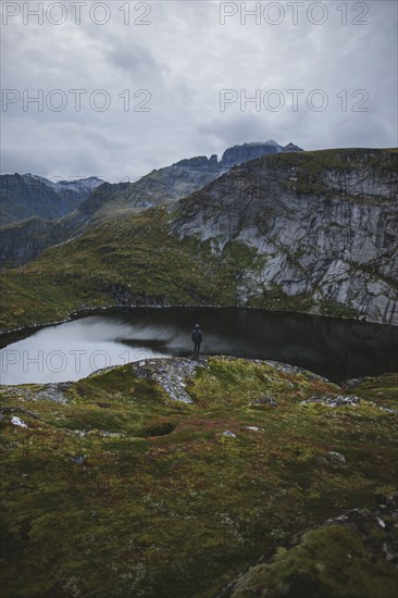 Man standing on rock by lake in Lofoten Islands, Norway