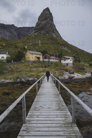 Man walking on bridge by cliff in Lofoten Islands, Norway