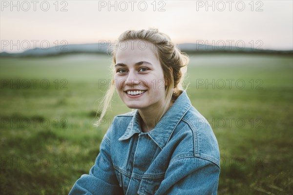 Smiling woman wearing denim jacket in field