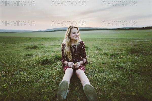 Smiling woman wearing dress sitting in field