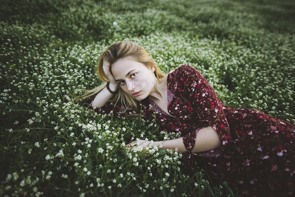 Woman wearing dress lying in meadow