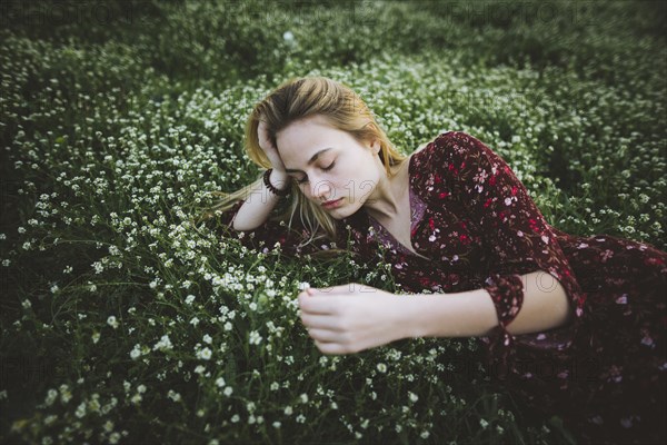 Woman wearing dress lying in meadow