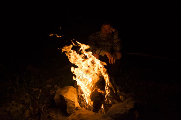 Man sitting by campfire at night