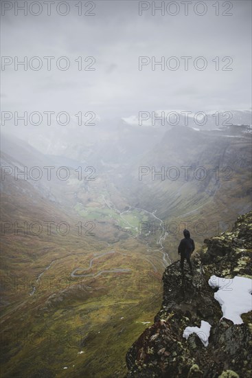 Man standing on Dalsnibba mountain overlooking valley in Geiranger, Norway