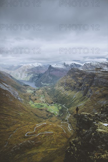Man standing on Dalsnibba mountain overlooking valley in Geiranger, Norway
