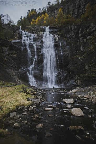 Person standing by Skjervefossen waterfall in Norway