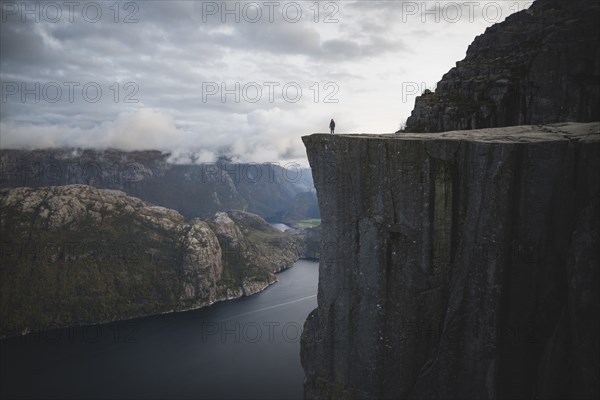 Person standing on Preikestolen cliff in Rogaland, Norway