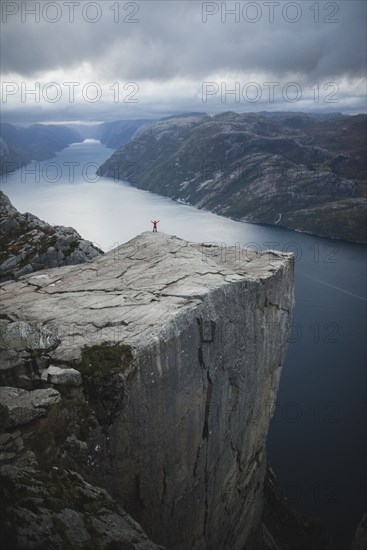 Person standing on Preikestolen cliff in Rogaland, Norway