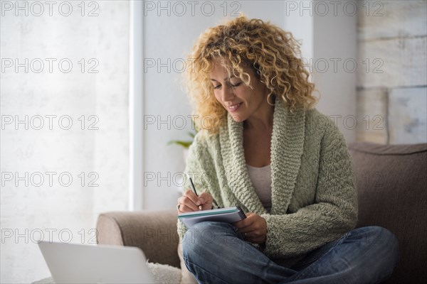 Smiling woman working with laptop on sofa