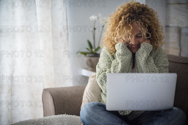 Smiling woman working with laptop on sofa