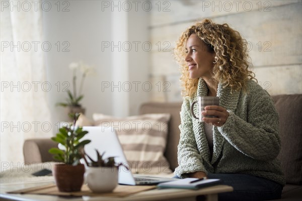 Smiling woman holding drink at laptop