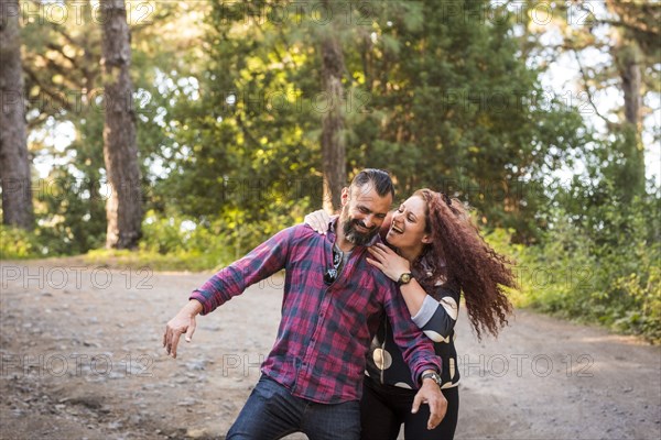 Smiling woman embracing smiling man by trees