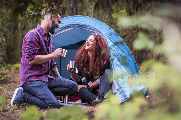 Smiling couple drinking by tent