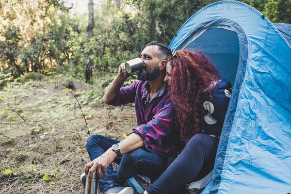 Smiling couple drinking by tent