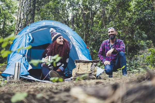 Smiling couple sitting by tent