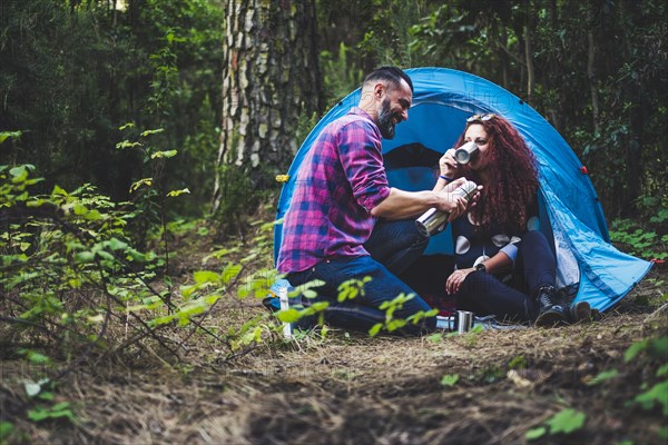 Smiling couple drinking by tent