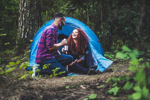 Smiling couple drinking by tent