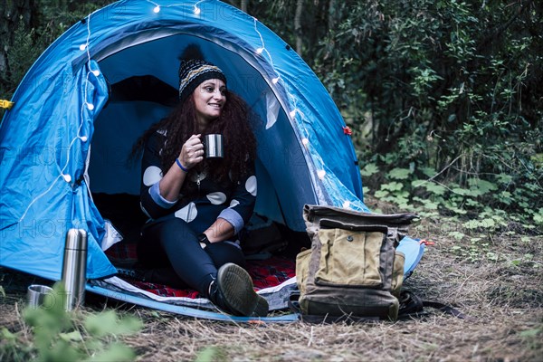 Smiling woman sitting in tent holding cup