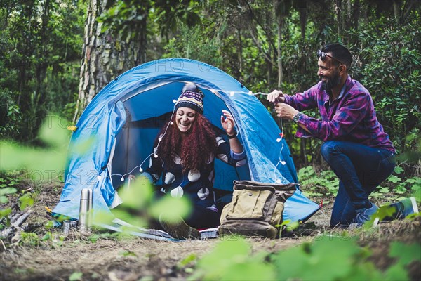 Smiling couple putting fairy lights on tent