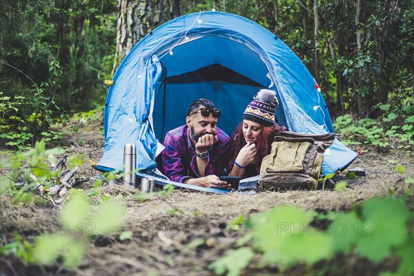 Couple lying in tent using tablet