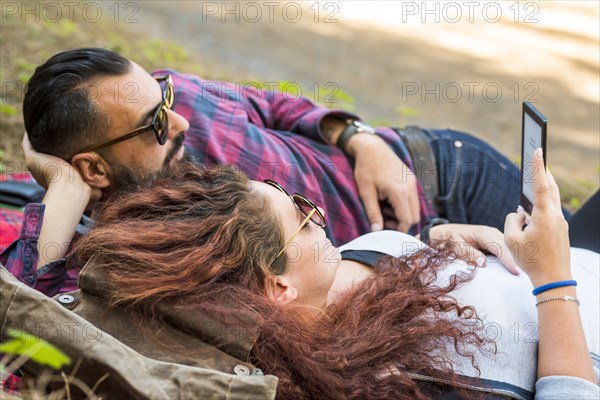 Couple lying on blanket using tablet