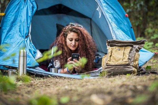 Woman lying in tent using smart phone