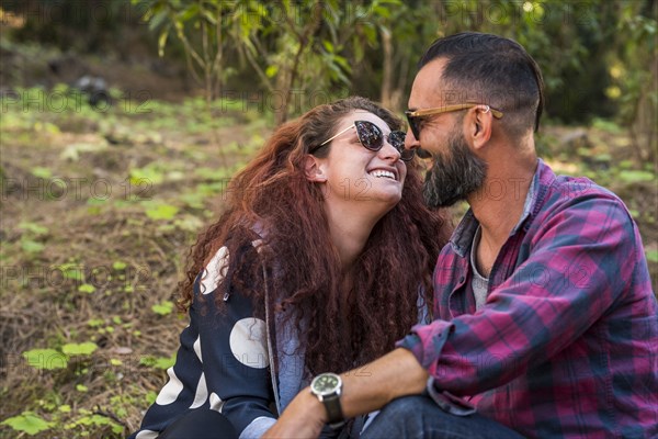 Smiling couple sitting by trees