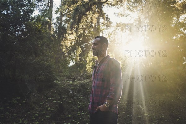 Man standing in sunlight in forest