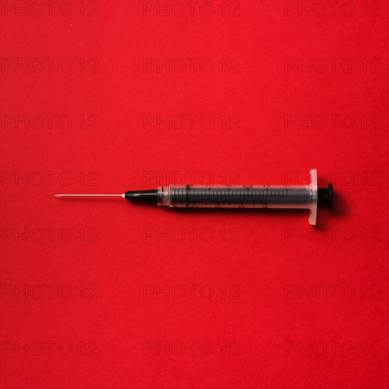 Syringe on red background