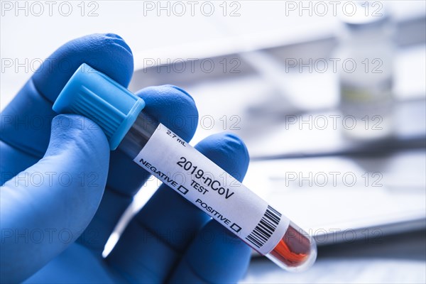 Close-up of gloved hand holding test vial labelled 2019-nCoV