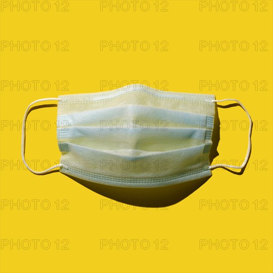 Surgical mask against yellow background