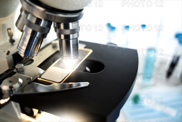 Laboratory microscope with a slide and vial of coronavirus test