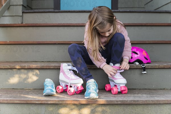 Little girl putting on roller skates