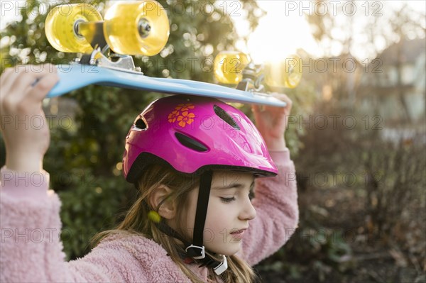 Girl carrying skateboard on head