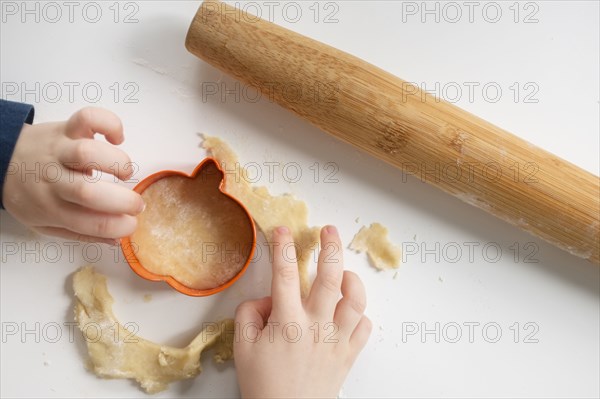 Close up of child making pumpkin shaped cookies